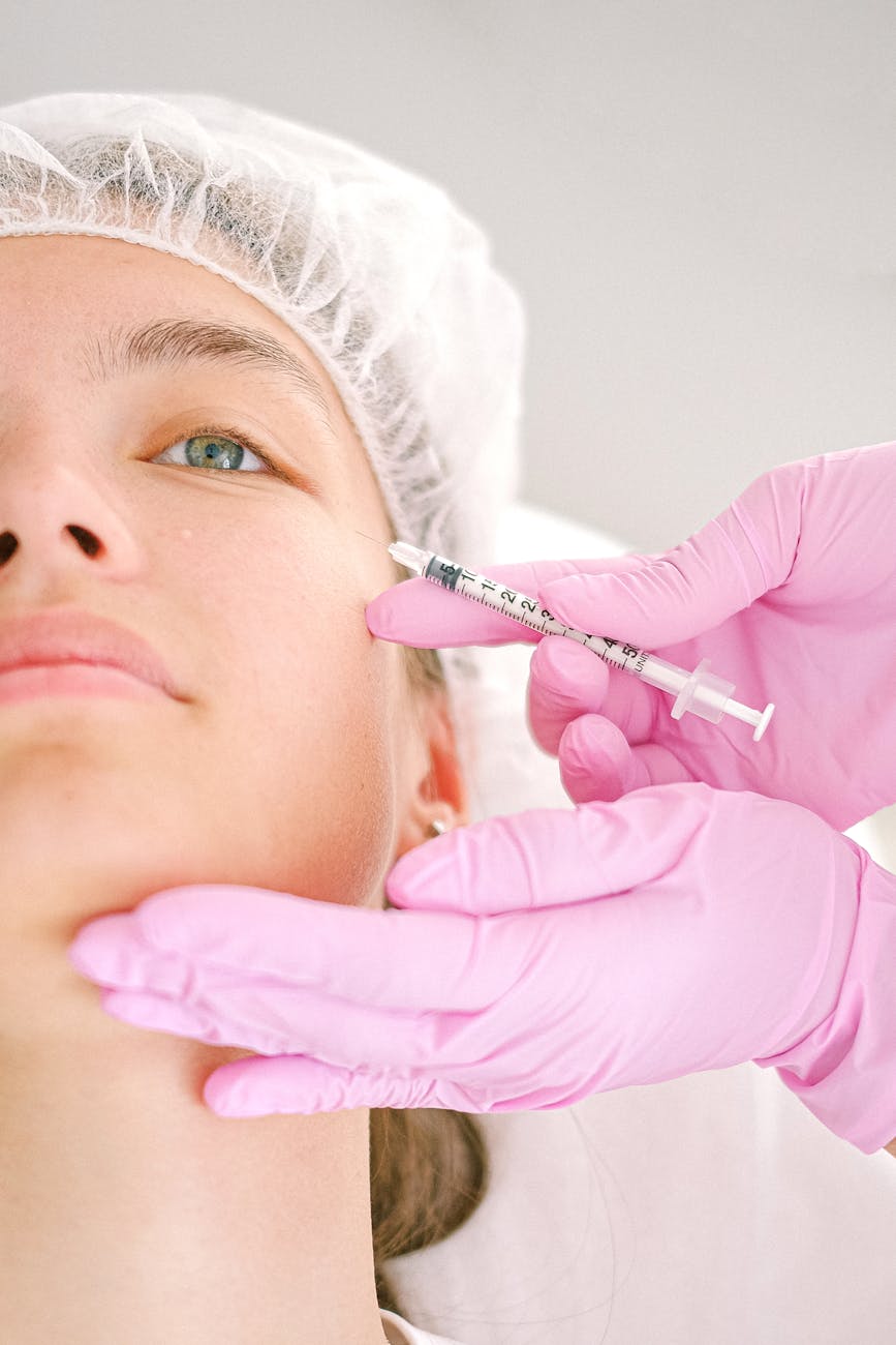 cosmetologist in pink gloves making injection in woman face