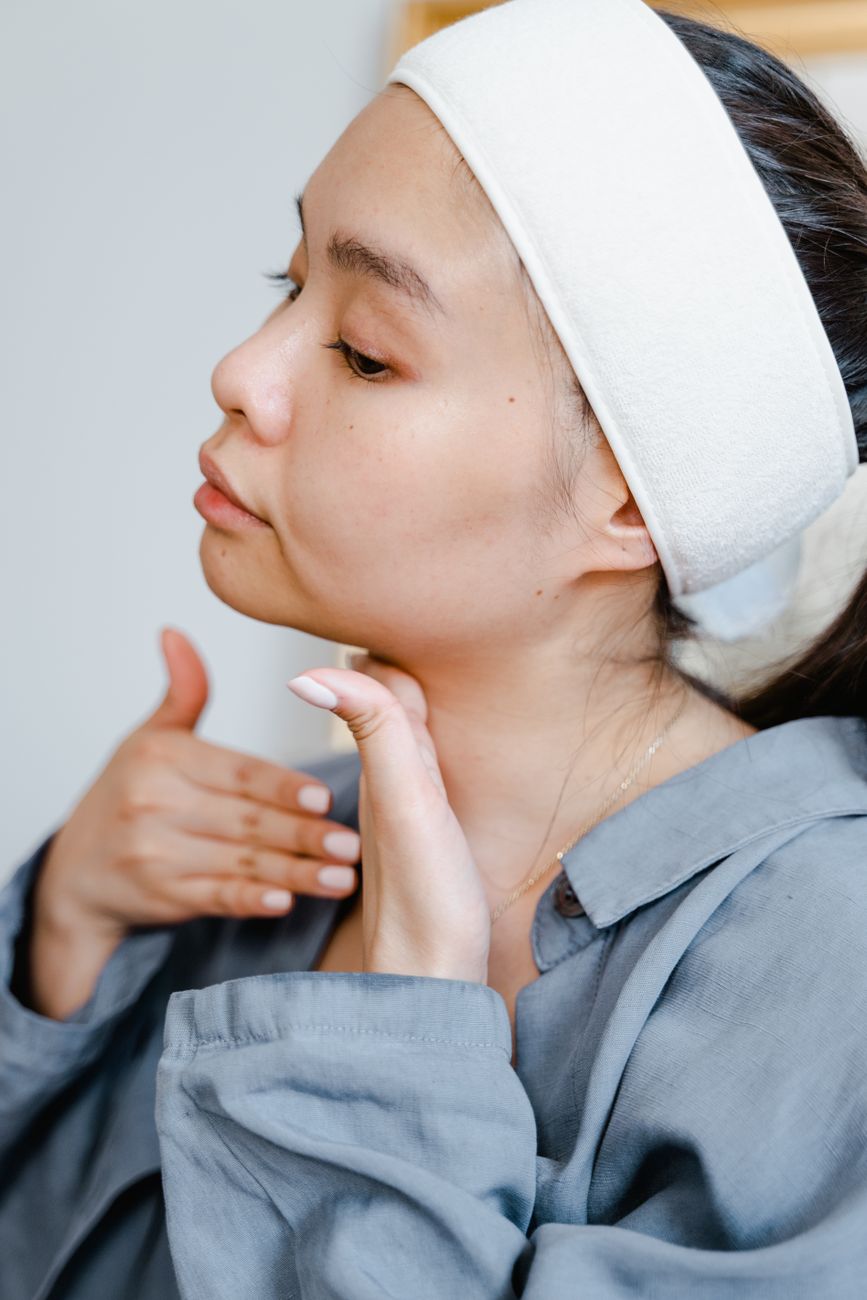 woman wearing facial headband touching her neck